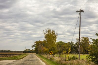 Electricity pylon on field against cloudy sky