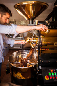 Young man preparing coffee in grinder at shop