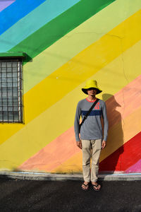 Full length of man standing against yellow wall