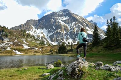 Woman on rock against sky by the alpine lake