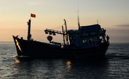 Boat on sea against sky during sunset