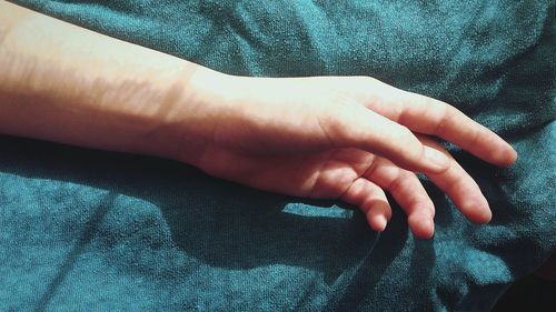 Close-up of cropped hand on bed