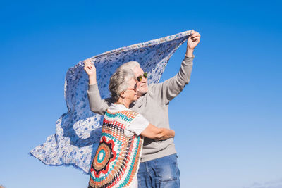 Senior couple standing with shawl against clear blue sky
