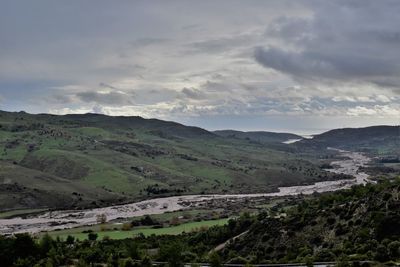 Scenic view of landscape against sky with swollen river snaking across diagonally