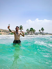 Full length of shirtless man drinking water in swimming pool