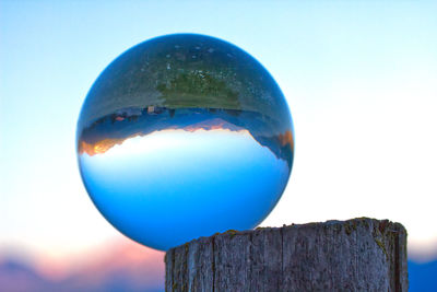 Close-up of crystal ball against blue sky