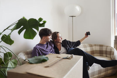 Young couple on sofa taking selfie