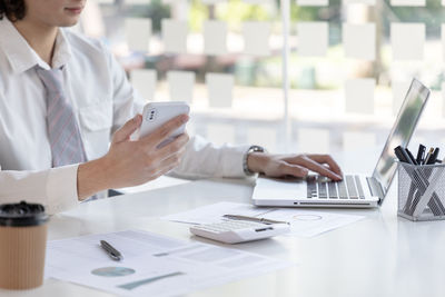 Midsection of woman using mobile phone at table