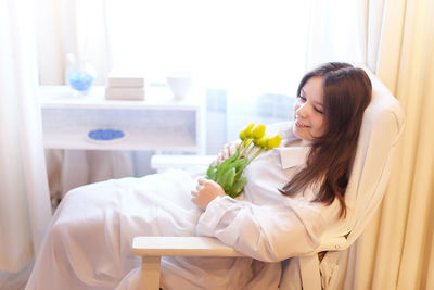 Portrait of young woman sitting on bed at home