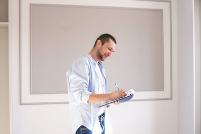 A satisfied man stands with a notebook and takes notes