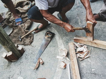 High angle view of man working with tools on wooden planks