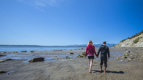 People walking on beach against clear sky