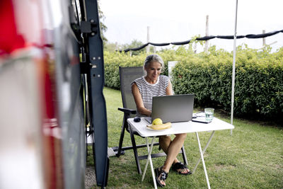 Freelancer using laptop sitting outside camper van