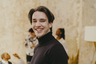 Portrait of happy businessman wearing turtleneck during event at convention center
