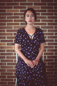 Portrait of a woman against brick wall