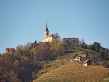 Houses by trees and buildings against clear sky