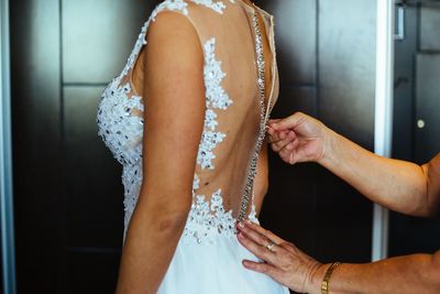 Cropped hands of woman dressing bride