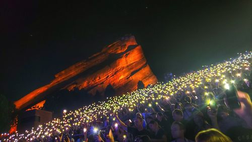 Group of people in illuminated street against sky at night