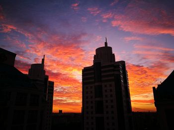 Low angle view of silhouette buildings against dramatic sky