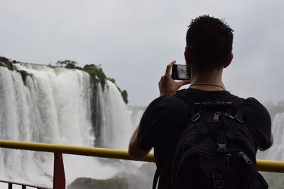 Rear view of man standing against waterfall