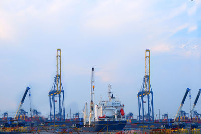 Cranes at commercial dock against sky