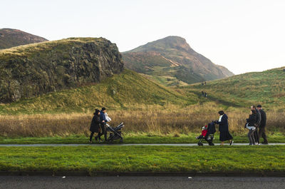 Rear view of people riding motorcycle on mountain against sky