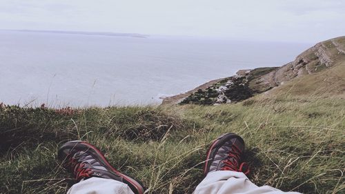 Low section of man standing by sea against sky