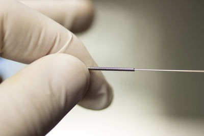 Cropped hand holding acupuncture needle in hospital