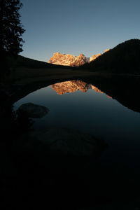 Scenic view of lake and silhouette mountains against clear sky