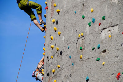 Low angle view of people climbing wall