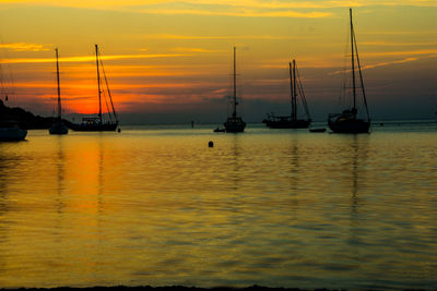 Silhouette boats moored on sea against sky during sunset