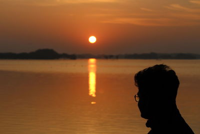 Silhouette man standing at beach during sunset