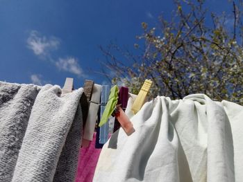 Low angle view of clothes drying on clothesline against blue sky
