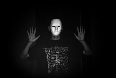 Man wearing mask standing against black background