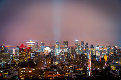 Illuminated cityscape against sky at night