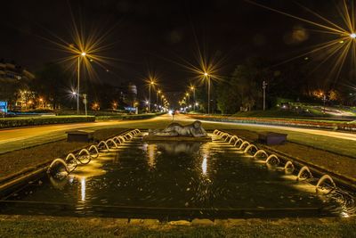 Light trails on bridge in city against sky at night