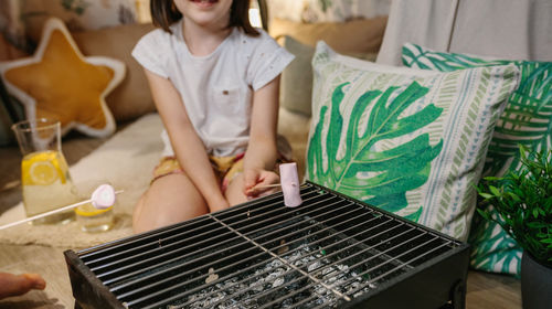 Midsection of girl grilling marshmellow on barbecue grill