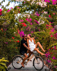 Romantic couple riding a bicycle surrounded by flowers