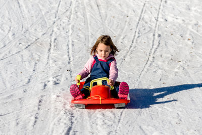 Cute girl tobogganing on snow