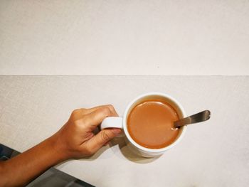 Close-up of hand holding coffee cup on table