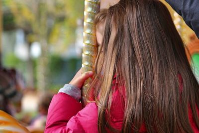 Close-up of girl sitting on carousel at amusement park