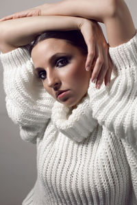 Fashionable girl in a white knitted sweater and leather pants stands on a white background