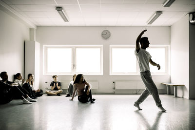 Male and female students looking at boy dancing in studio at high school