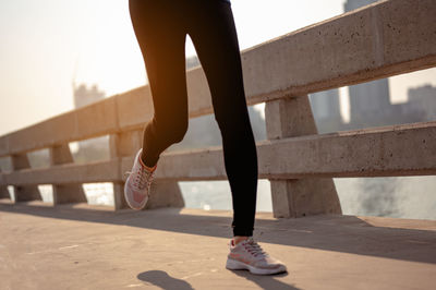 Low section of woman standing on railing