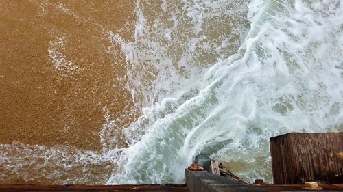 High angle view of waves breaking against sea