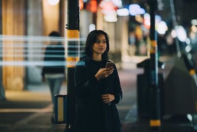 Young woman using mobile phone in city