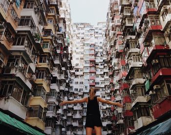 Rear view of woman standing amidst buildings in city