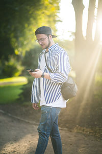 Young man using mobile phone while walking in park