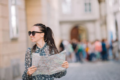 Portrait of young woman wearing sunglasses standing in city