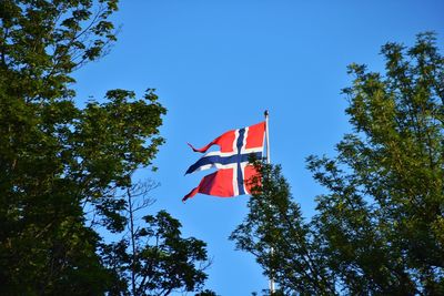 Low angle view of flag against clear blue sky